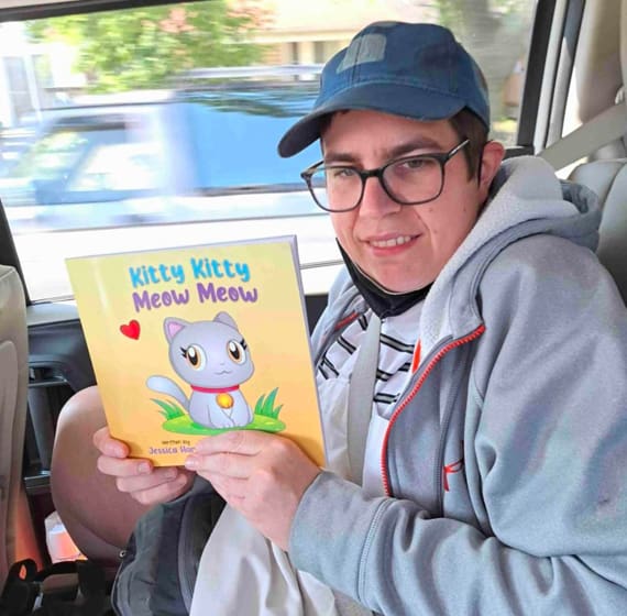 eddie sitting in a car holding up a book